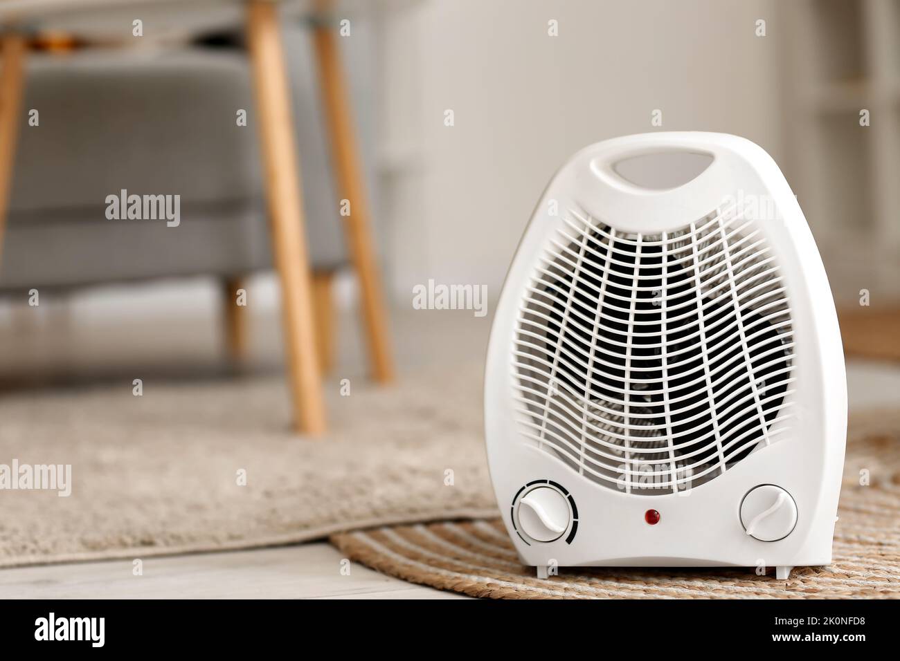 Electric fan heater on rug in living room Stock Photo