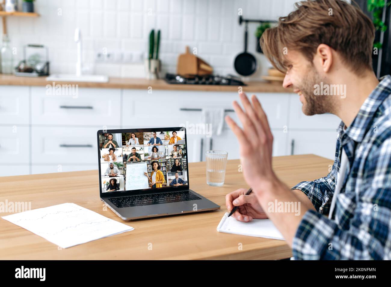 Online lesson, distance education. Side view of a smart caucasian male student and group of multiracial people on a laptop screen. Clever guy listening to an online lecture, webinar, gain knowledge Stock Photo