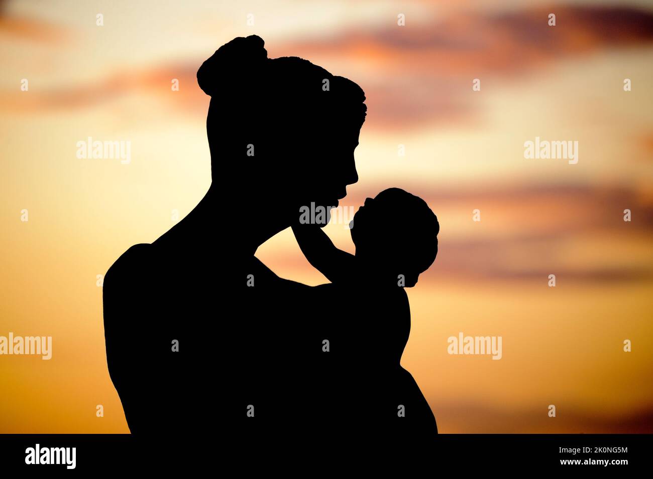 A sculpture of a mother with a young child in a small park in Sorrento on the Amalfi Coast of Italy at sunset. Stock Photo