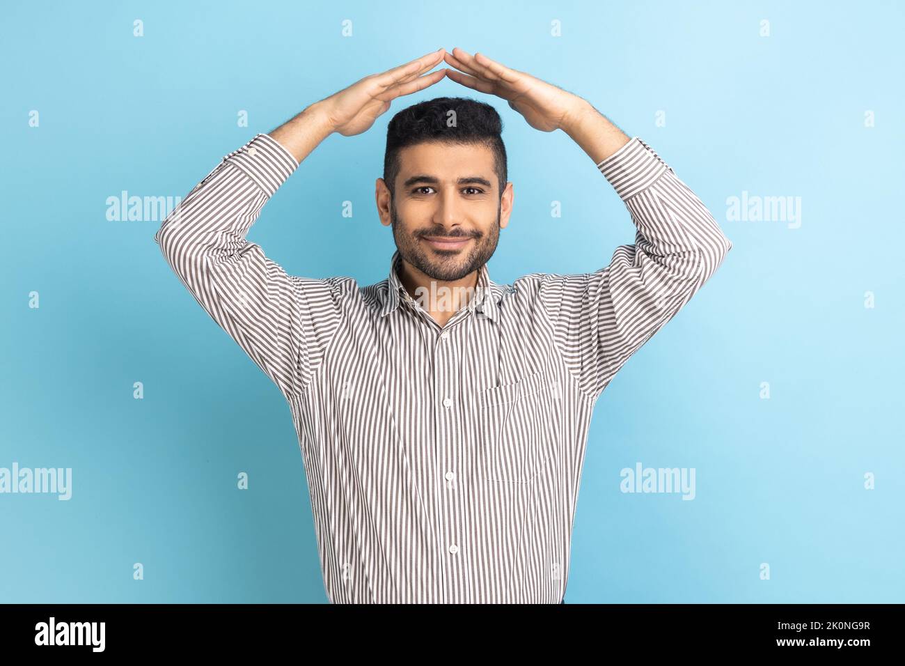Portrait of friendly businessman holding roof hand gesture over head and smiling, feeling