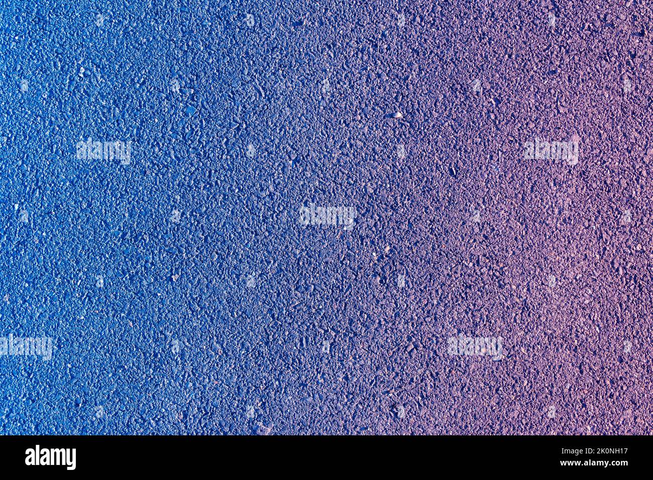 texture of a new asphalt pavement with small stone and sand with a purple-blue color gradient overlaid, selective focus Stock Photo