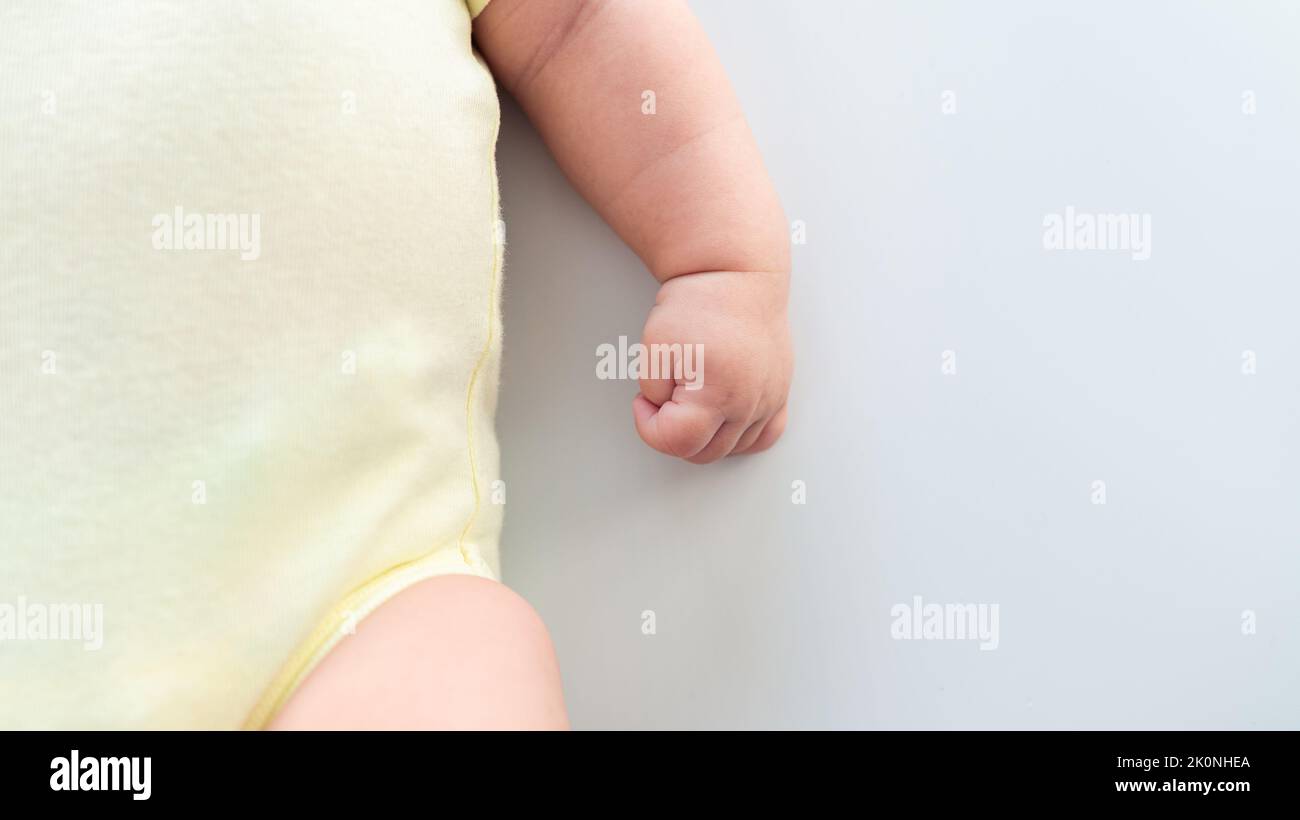 Hand of little baby on white sheet bed background with day light. Cute boy and chubby hands of a child. A newborn age of 3 months. Happy family matern Stock Photo