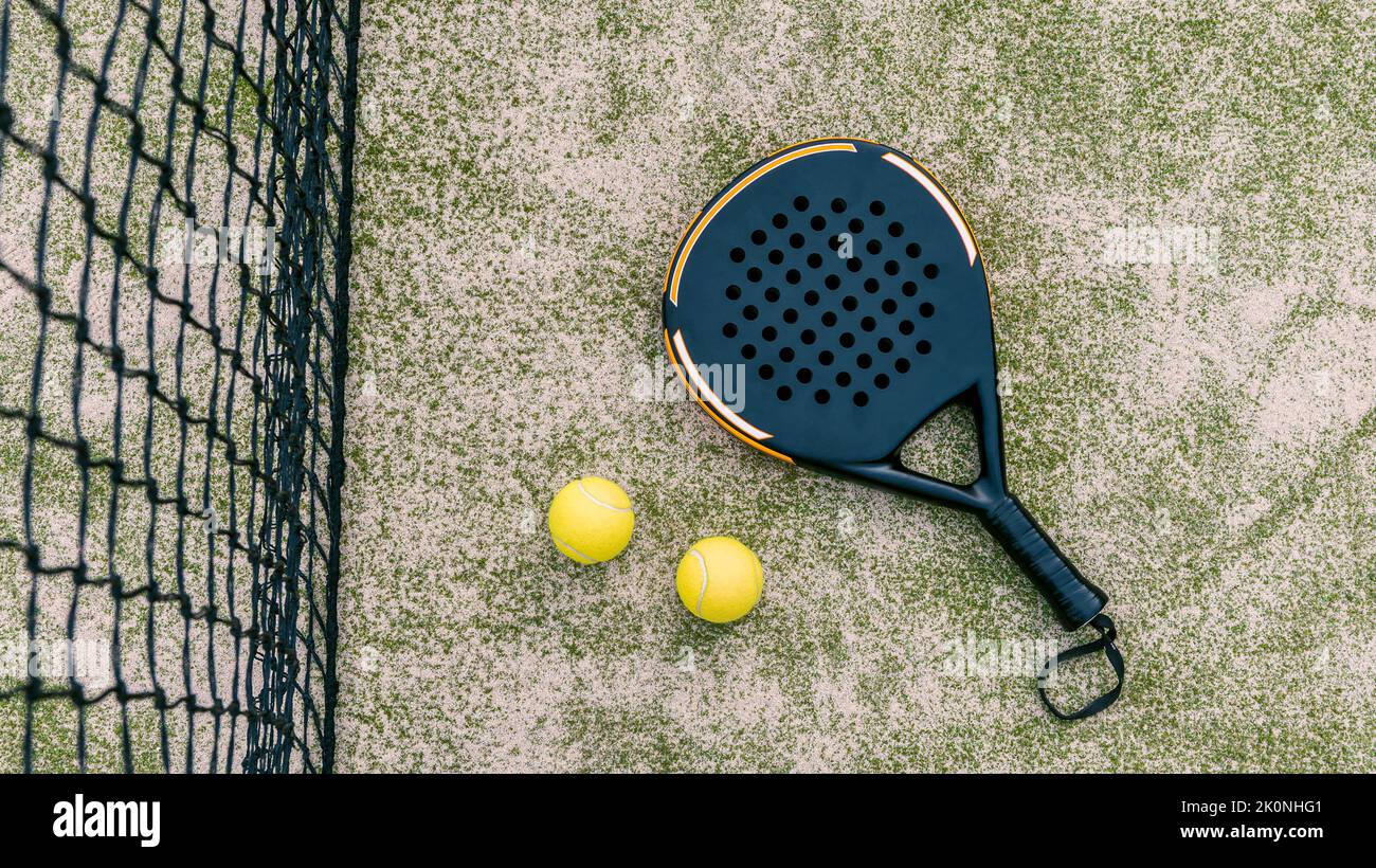 Top view of yellow balls on floor near of padel tennis racket in green court outdoors with natural lighting. Paddle is a racquet game. Professional sp Stock Photo