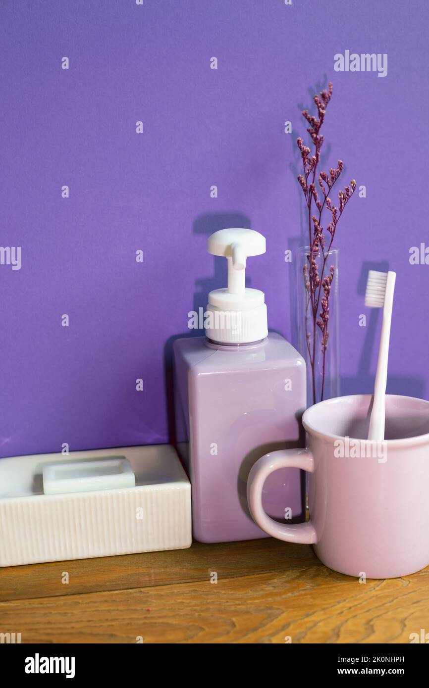 Bathroom accessories hygiene objects on wooden table. purple wall background Stock Photo