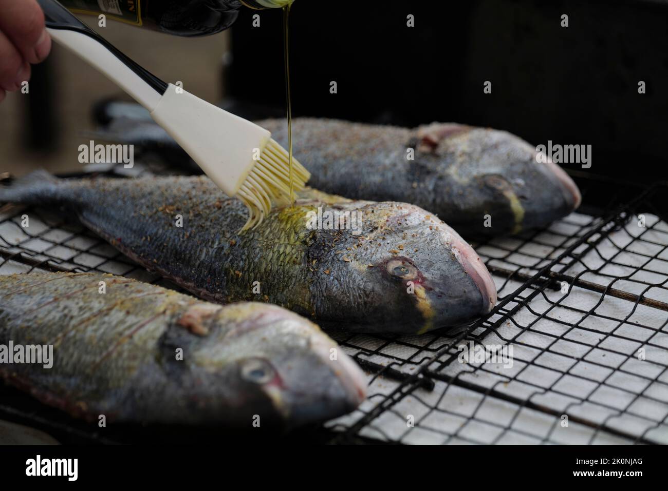 cooking sea fish. Raw dorado fish with spices on bbq mesh Stock Photo ...