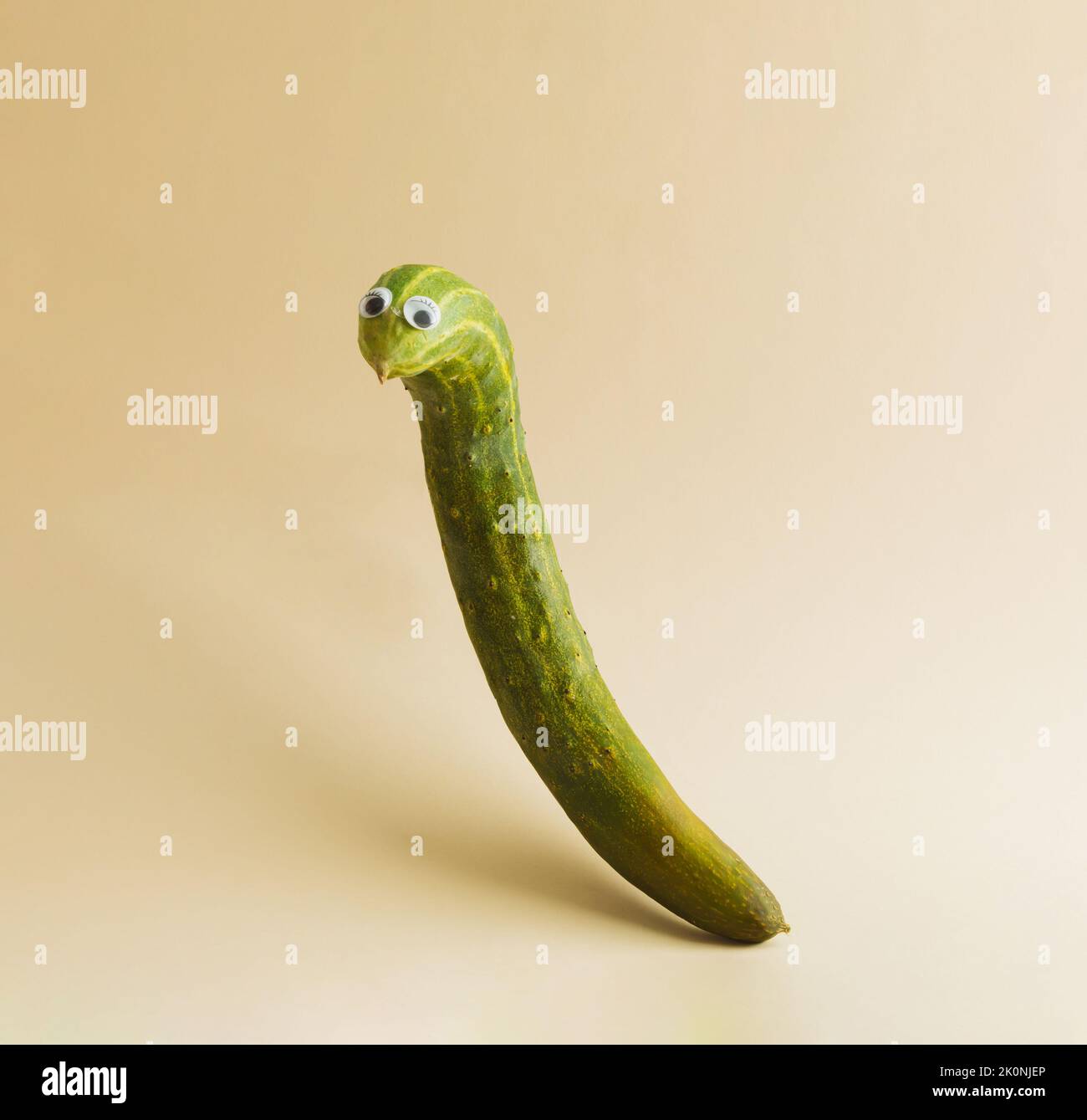 Funny cucumber with eyes on beige background. Halloween holiday idea. Creative still life, copy space. Stock Photo