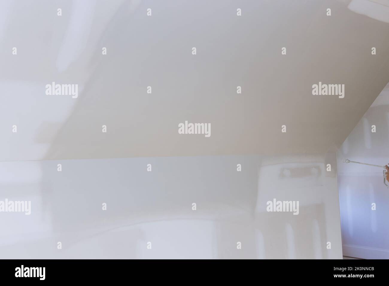 Using a spray gun equipped with a primer, the worker paints walls and