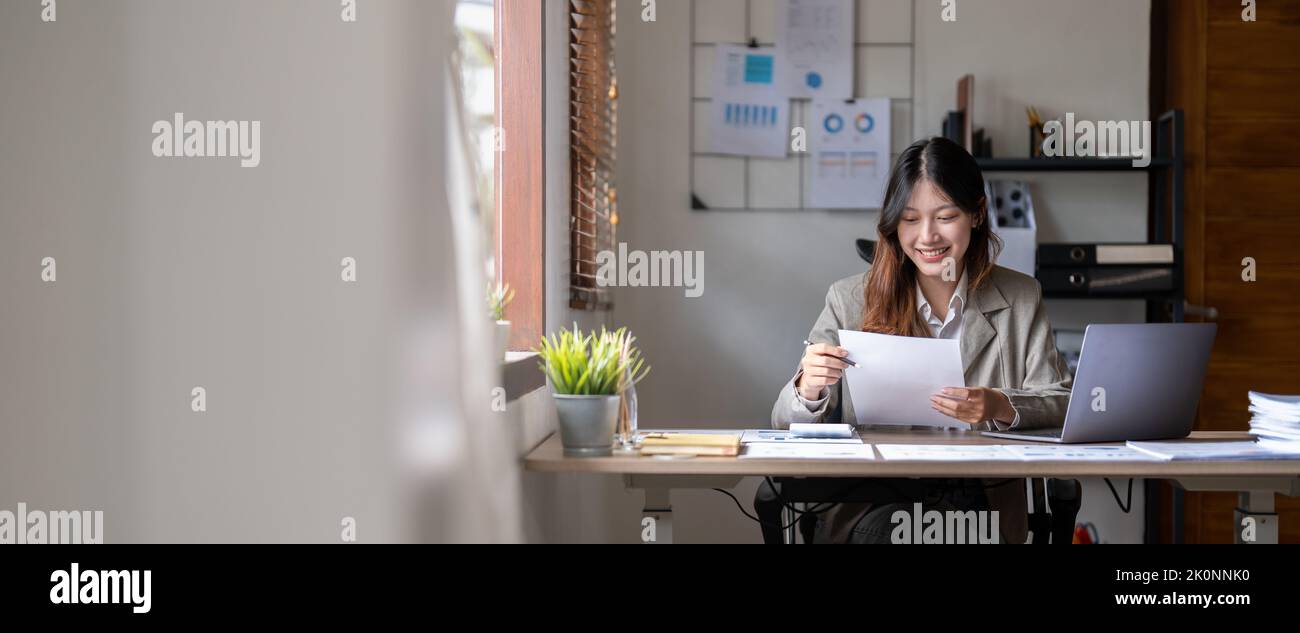 Attractive confident smiling asian woman paperwork chart report at home office. accounting financial concept. Stock Photo