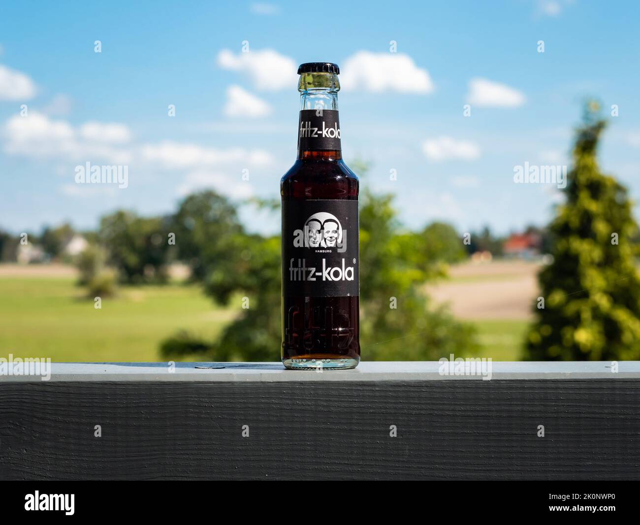 Fritz Kola bottle in front of a beautiful nature landscape. Serving a chilled beverage as refreshment on a hot summer day. Black sweet drink. Stock Photo