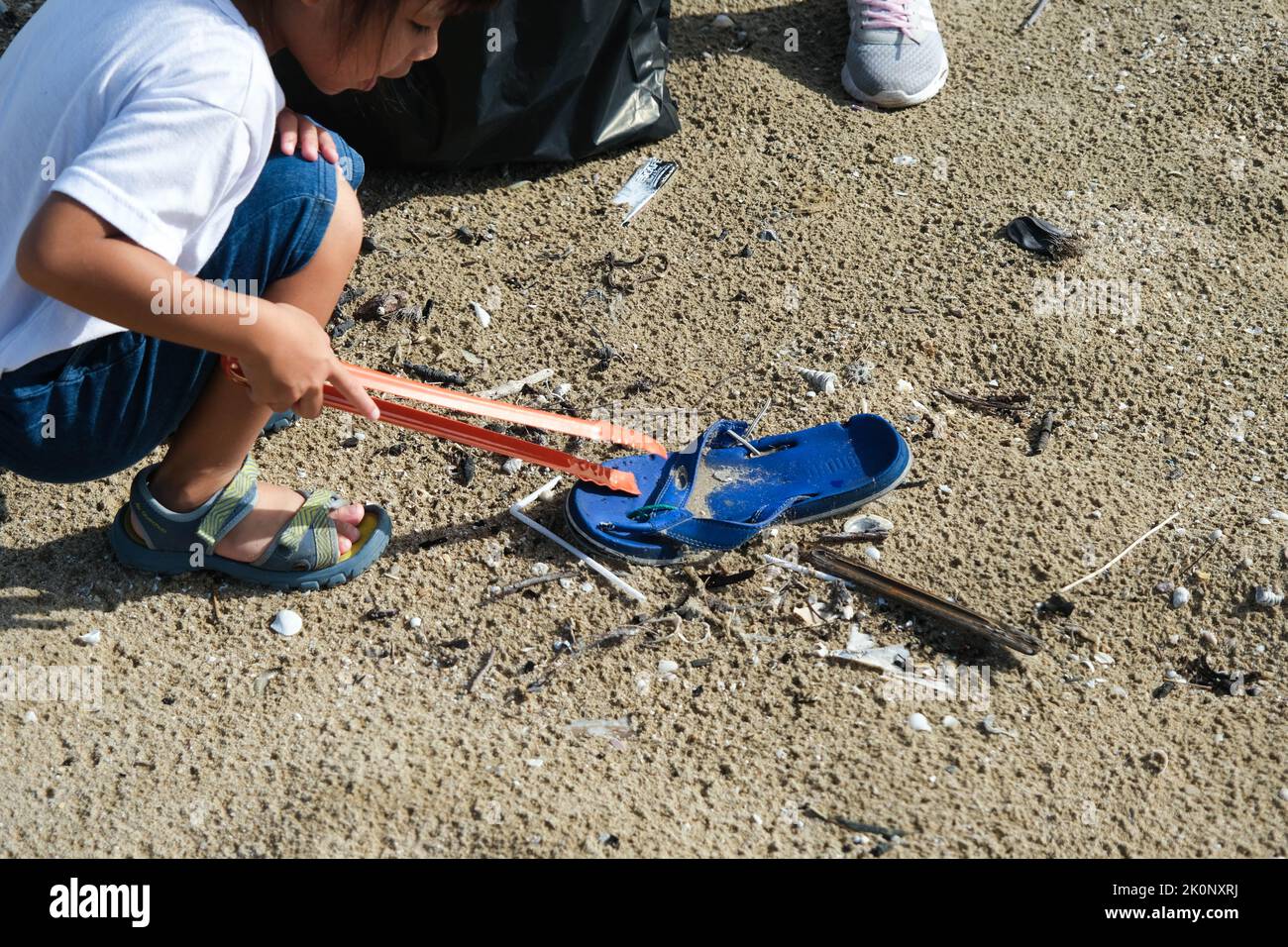 Mother and daughters in gloves cleaning up the beach. Group of young