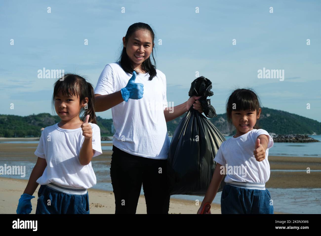 Mother and daughters in gloves cleaning up the beach. Group of young