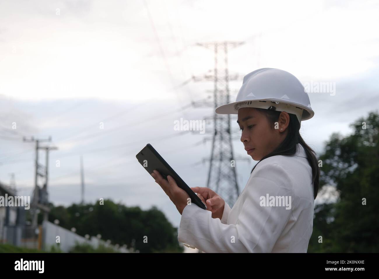 Asian female electrical engineer working on tablet near high voltage