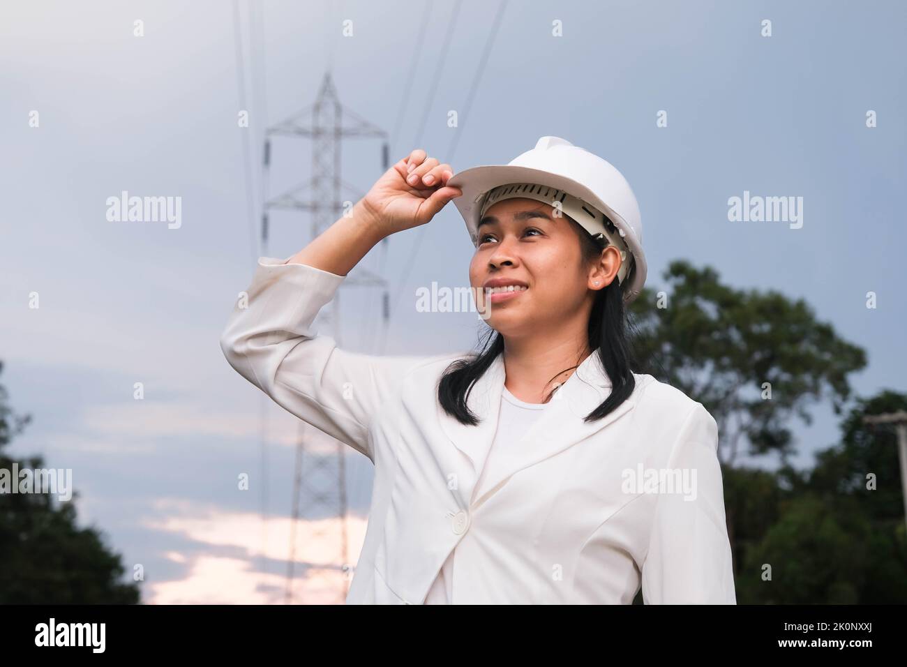 Asian female electrical engineer working near high voltage pole