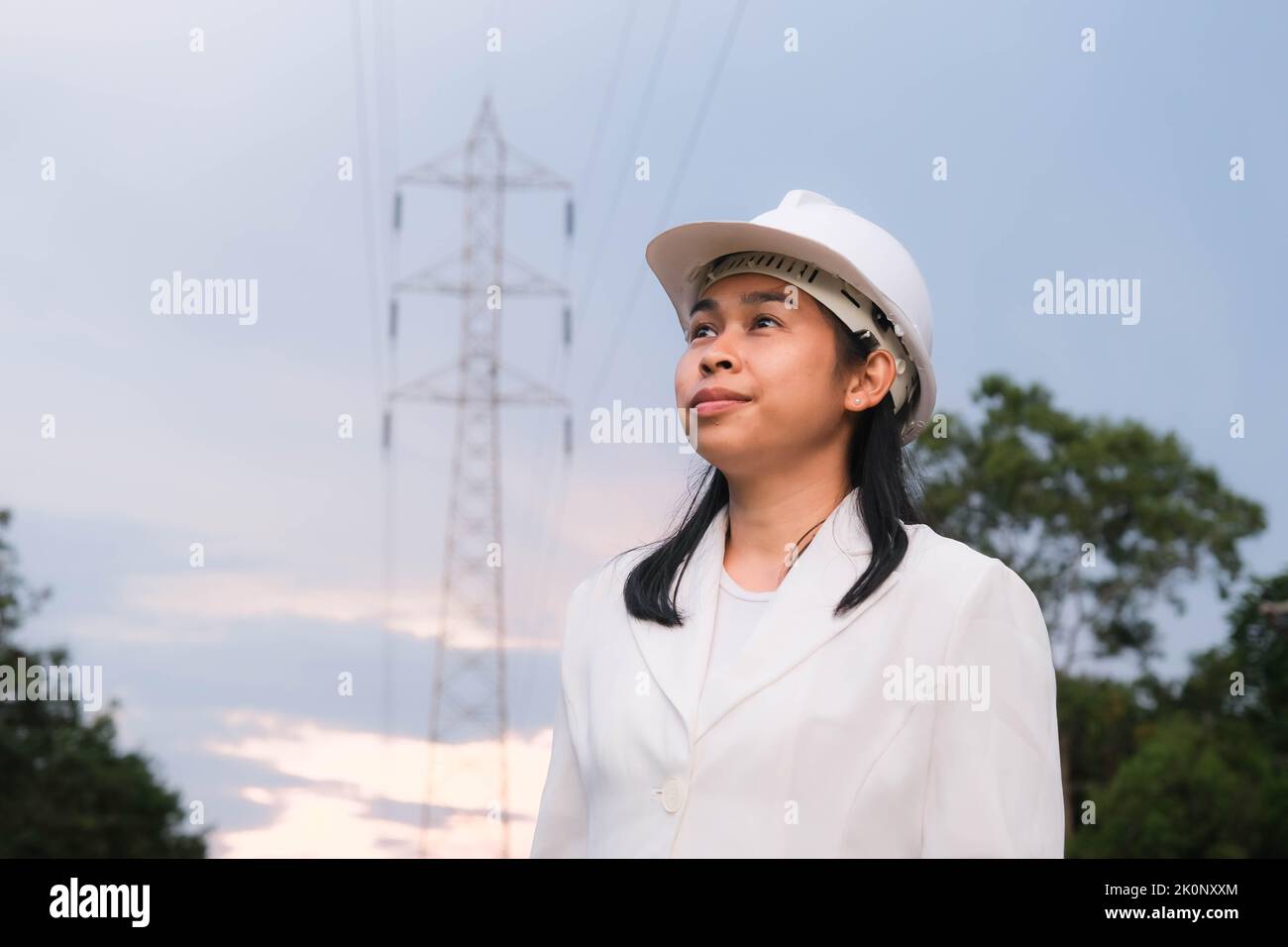 Asian female electrical engineer working near high voltage pole