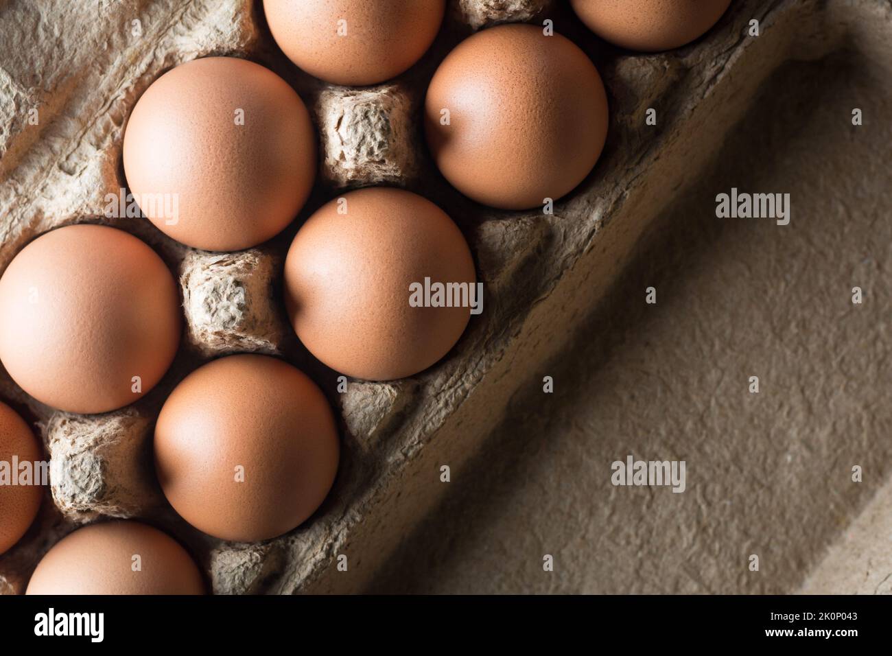 fresh brown chicken eggs in an egg box, taken straight from above with space for text and dramatic lighting, healthy organic food concept Stock Photo
