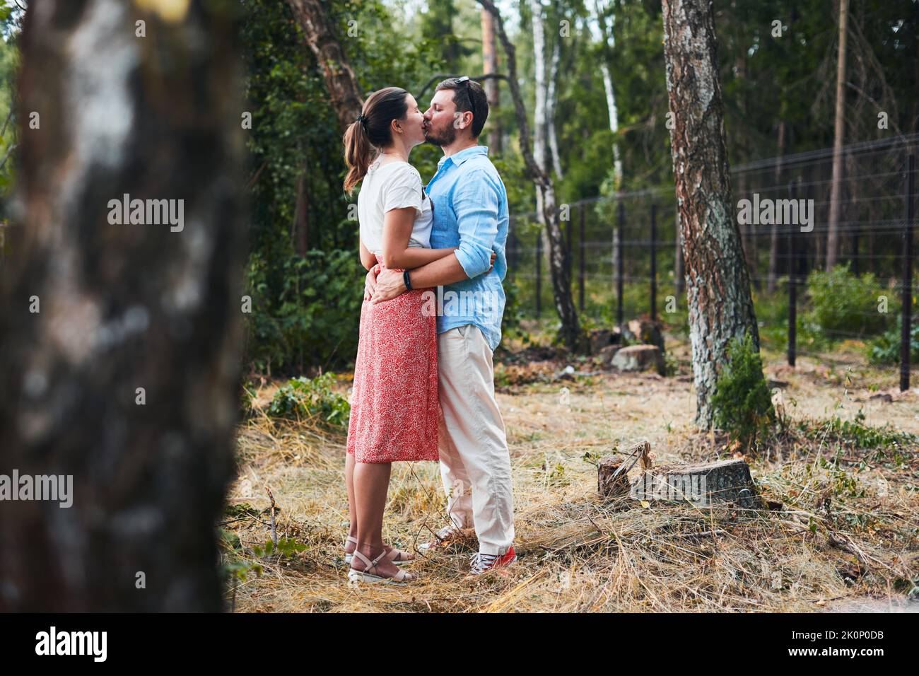 Portrait of a young couple kissing on a date in the woods. Front view. Stock Photo