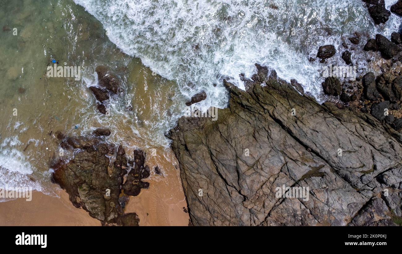 Aerial view of sea waves crashing on rocks cliff in the blue ocean. Top view of coastal rocks in Phuket ocean. Landscape view point of Laem Phromthep Stock Photo