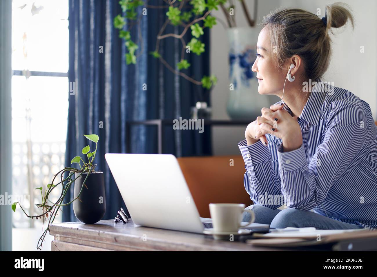 mature professional asian woman working from home looking away thinking Stock Photo