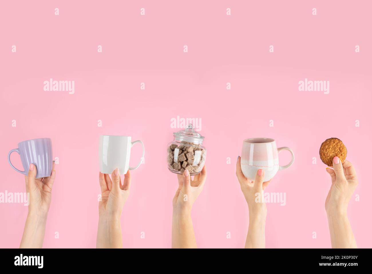 Arms raised up holding coffee cup on pink background. Concept photo. Front view Stock Photo
