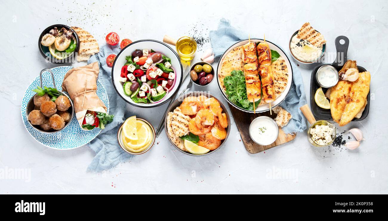 Greek food background. Meze, gyros, souvlaki, fish, pita, greek salad, tzatziki, assortment of feta, olives and meatballs. Traditional different greek Stock Photo