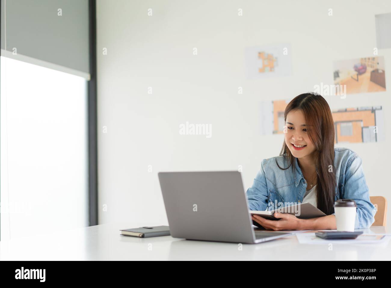 Construction design concept, Female architect taking notes while working about house plan on laptop. Stock Photo
