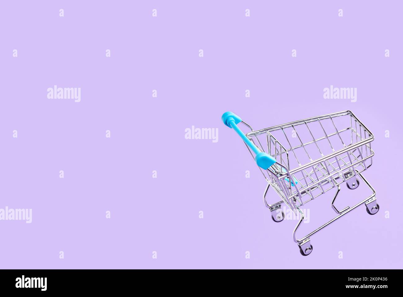 Empty shopping cart with light blue details flying on a pastel lilac background. Simple design with copy space. Concepts: market deals, seasonal sales Stock Photo