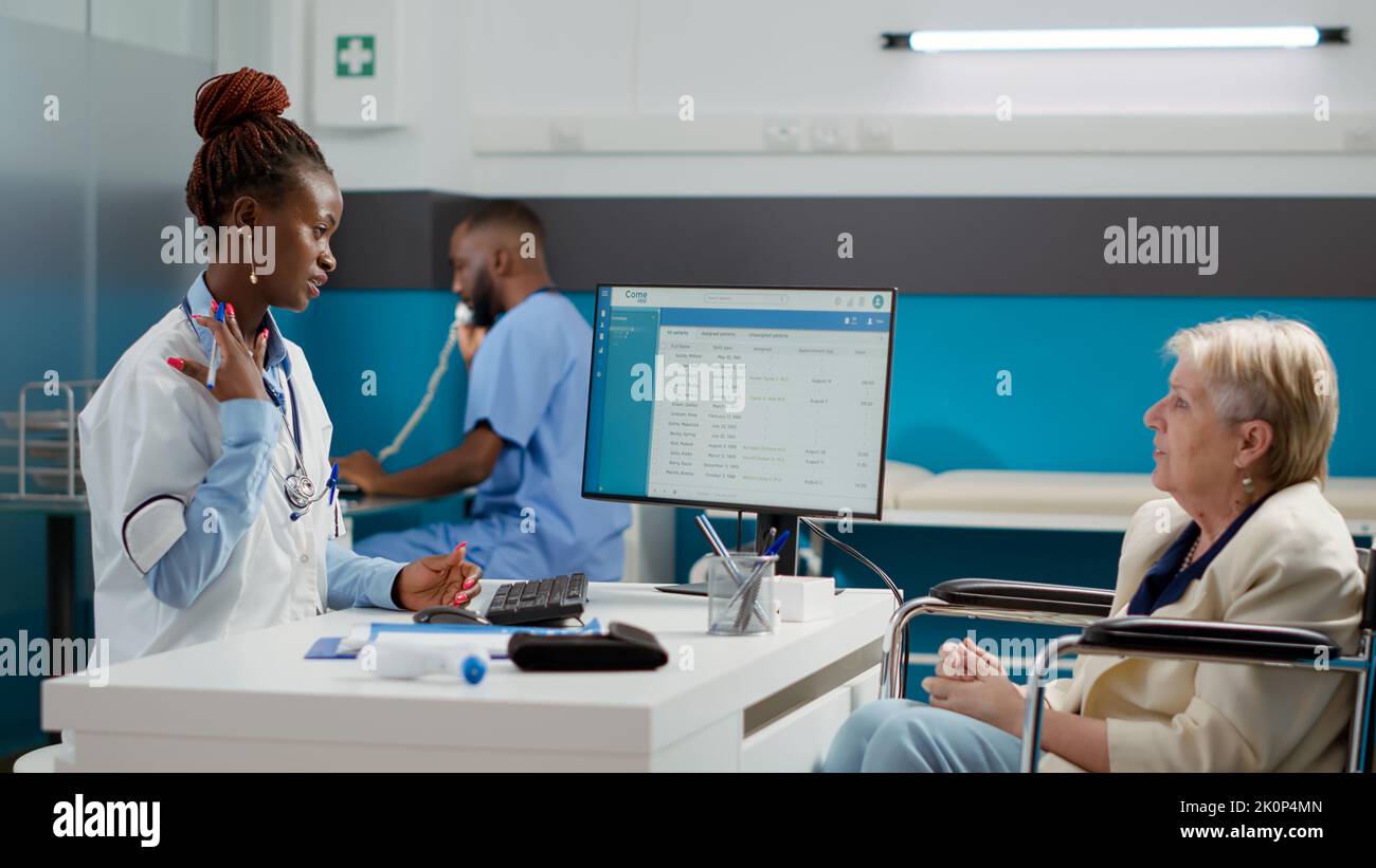 African american doctor doing checkup visit with female wheelchair user