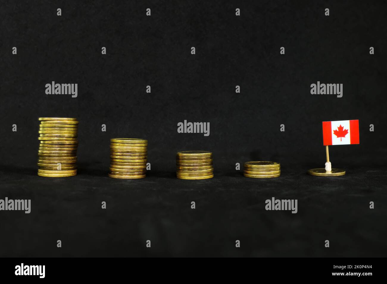Canada economic recession, financial crisis and currency depreciation concept. Canadian flag in decreasing stack of coins in dark black Stock Photo