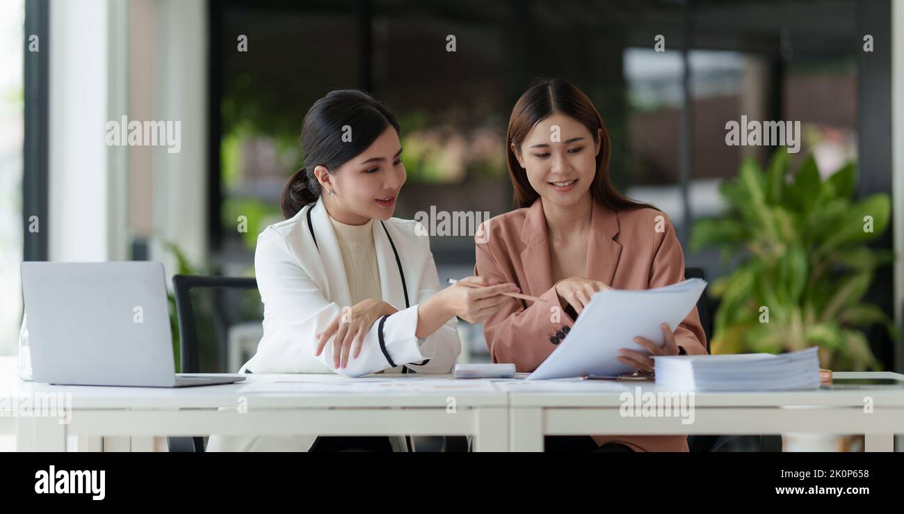 Asian Business Woman or Accountant do math and analyze with calculator and paperwork on desk, account, consult, audit and saving concept Stock Photo