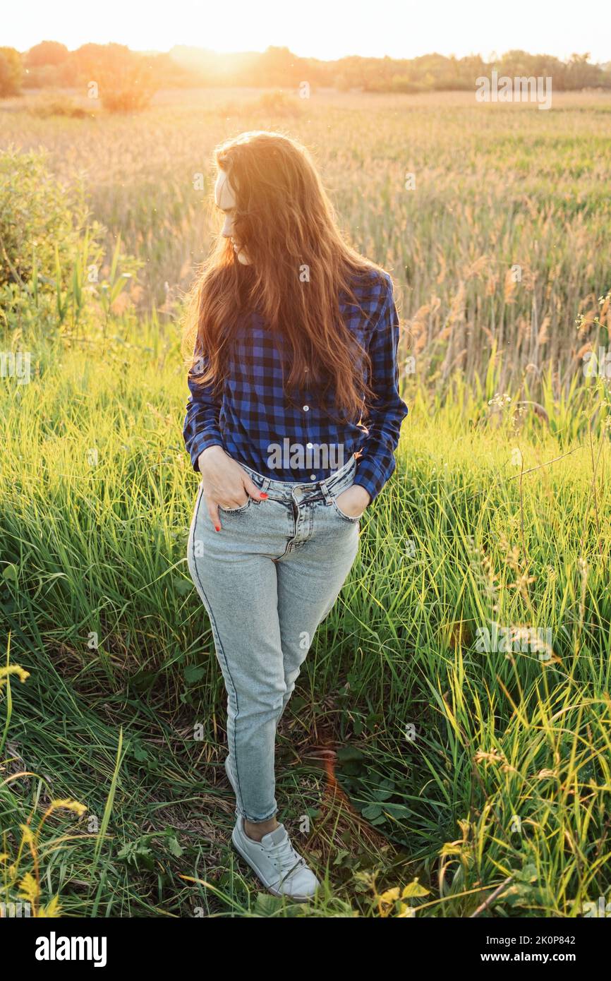 Portrait of a beautiful young woman on meadow watching the sunset ...