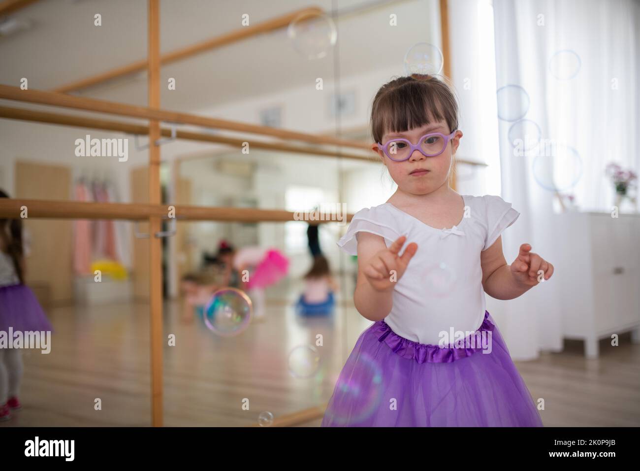 Little girl with down syndrome at ballet class in dance studio. Concept
