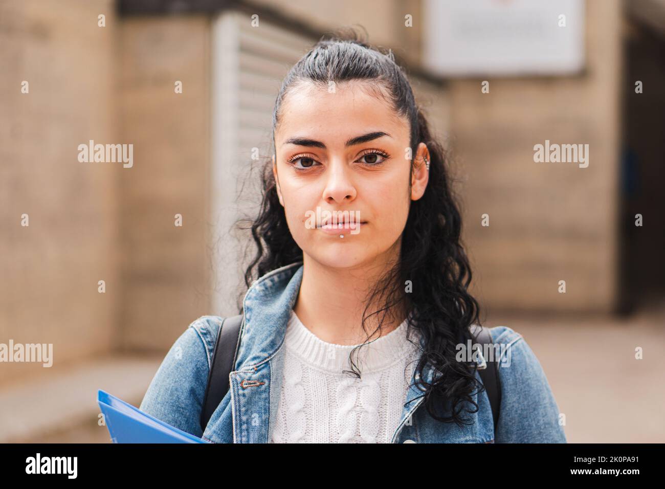 Young hispanic serious girl brunette student looking serious at camera. Juvenile teenage lady standing at university campus. Education concept. Stock Photo