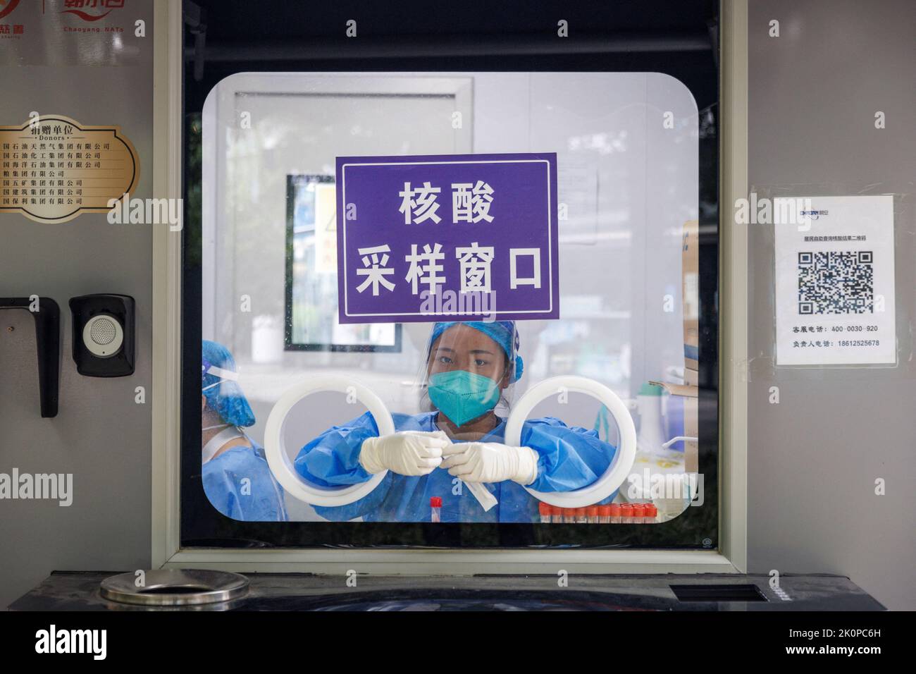 A pandemic prevention worker sits in a nucleic acid testing booth following a coronavirus disease (COVID-19) outbreak in Beijing, China, September 13, 2022. REUTERS/Thomas Peter Stock Photo