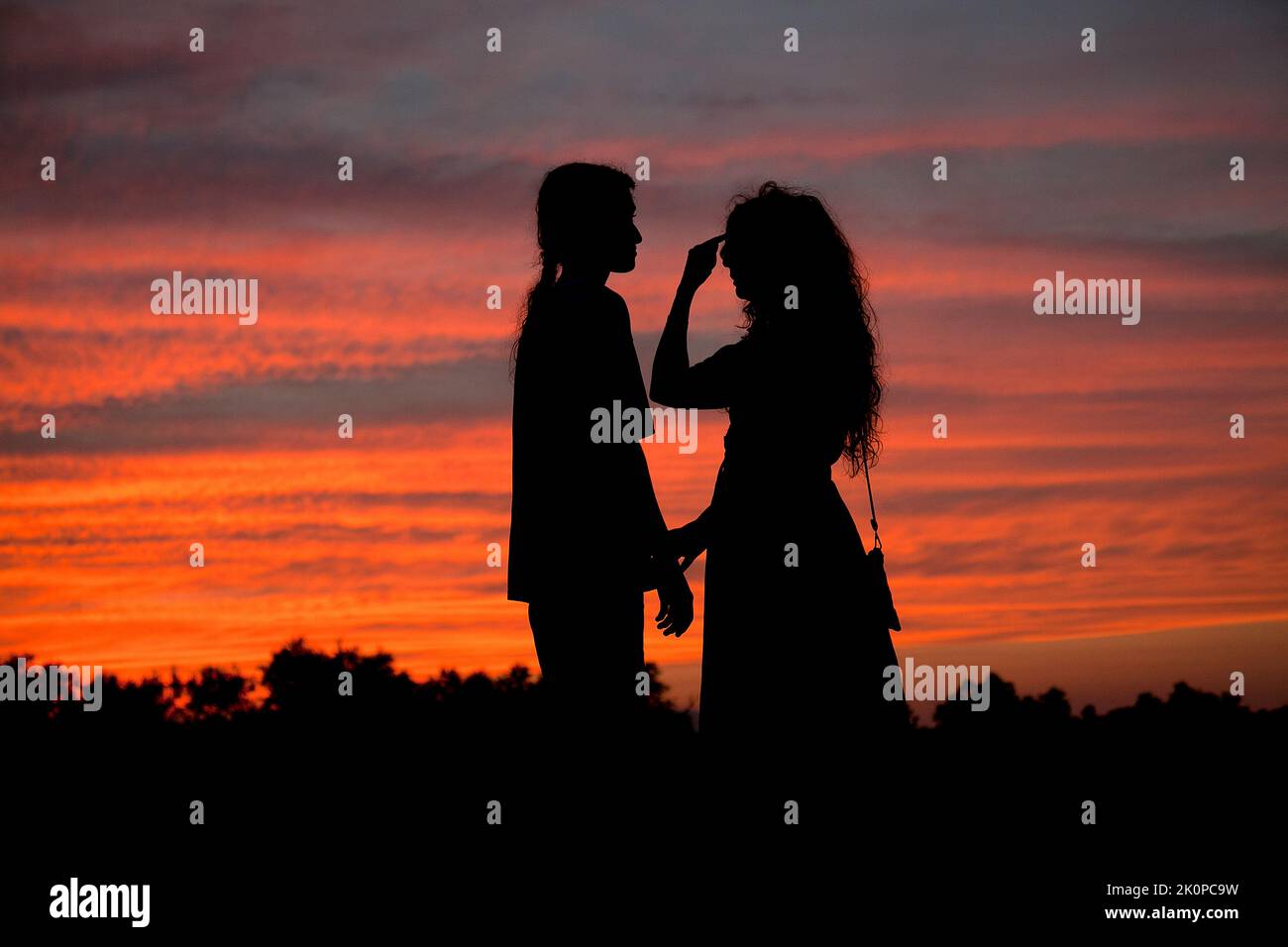 Mother and teenage son silhouetted against Shepherd's sunset. Stock Photo