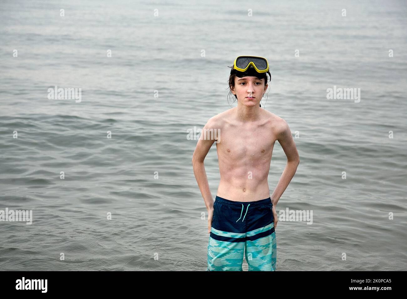 Teenage boy standing at water's edge. Stock Photo