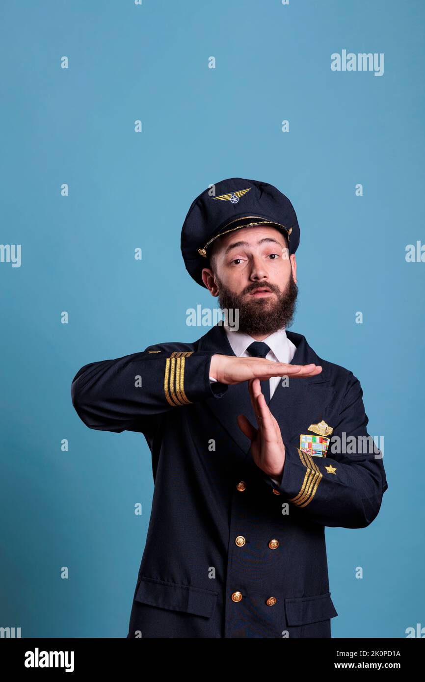 Airplane pilot showing time out gesture with hands, looking at camera with stop signal. Aviation academy plane captain front view, airforce aviator with timeout sign, take break, interruption Stock Photo