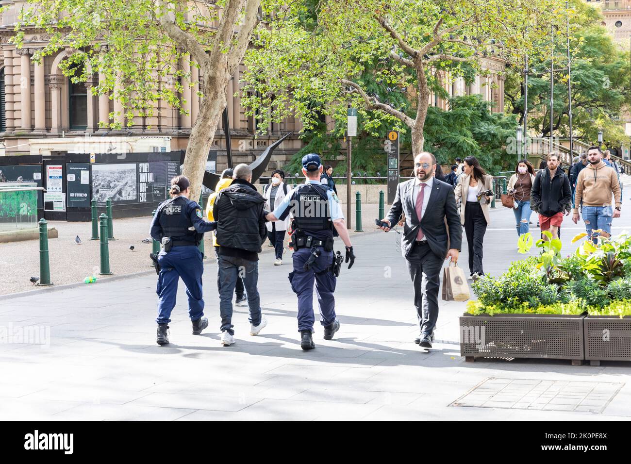 Australian NSW Police in Sydney escort an arrest male along George street in Sydney, male and female police officer armed and in uniform,Sydney Stock Photo