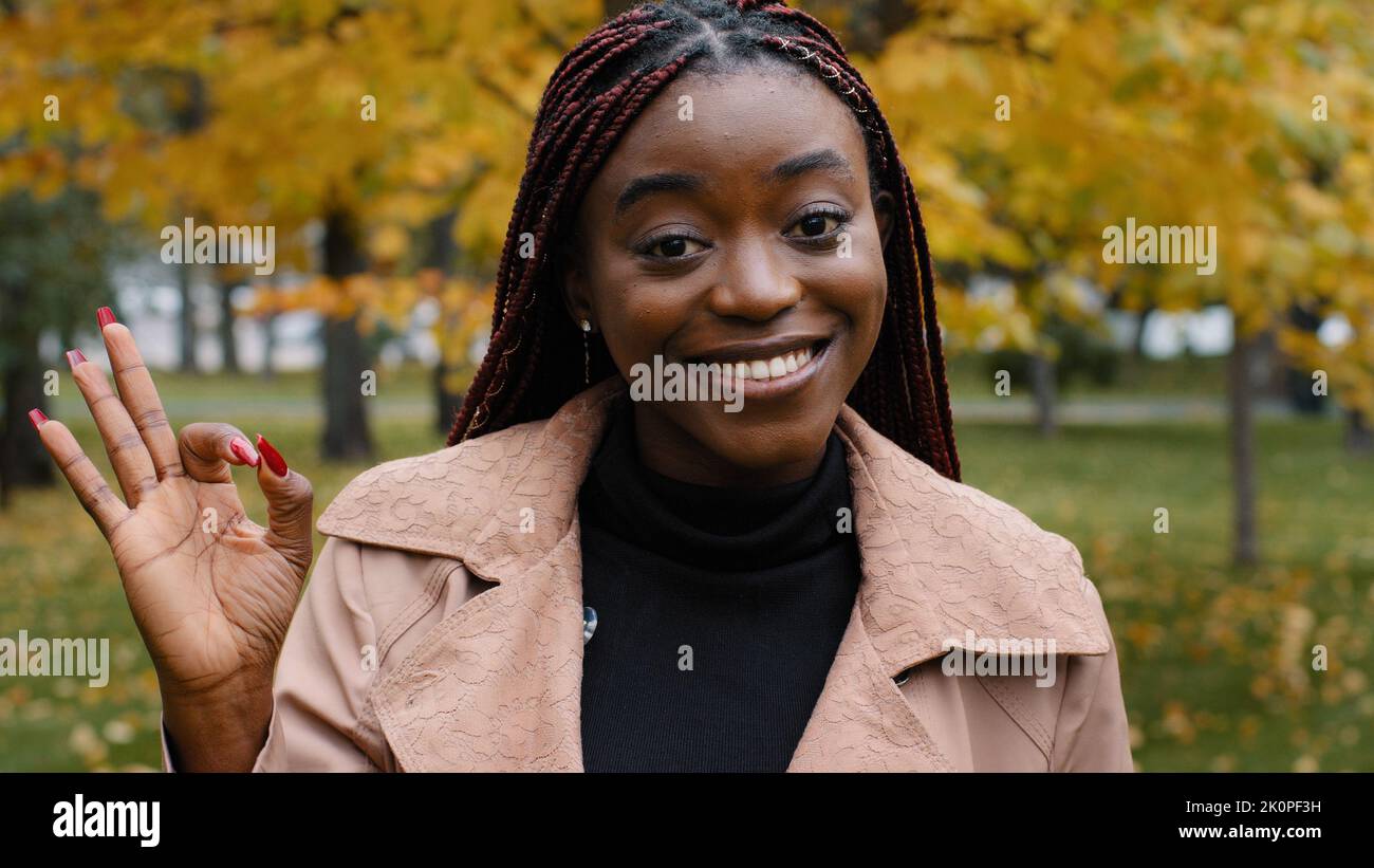Close-up young happy joyful african american woman looking at camera posing outdoors showing ok gesture of approval recommendation sign good choice Stock Photo
