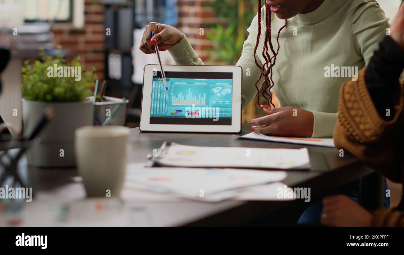 Diverse team of people analyzing data charts report on digital tablet ...