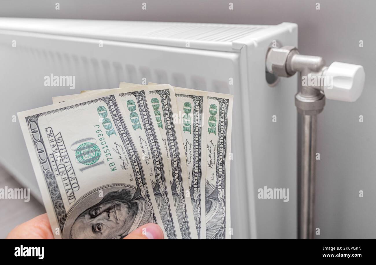 Dollars on the heater. Payment for heating. Stock Photo