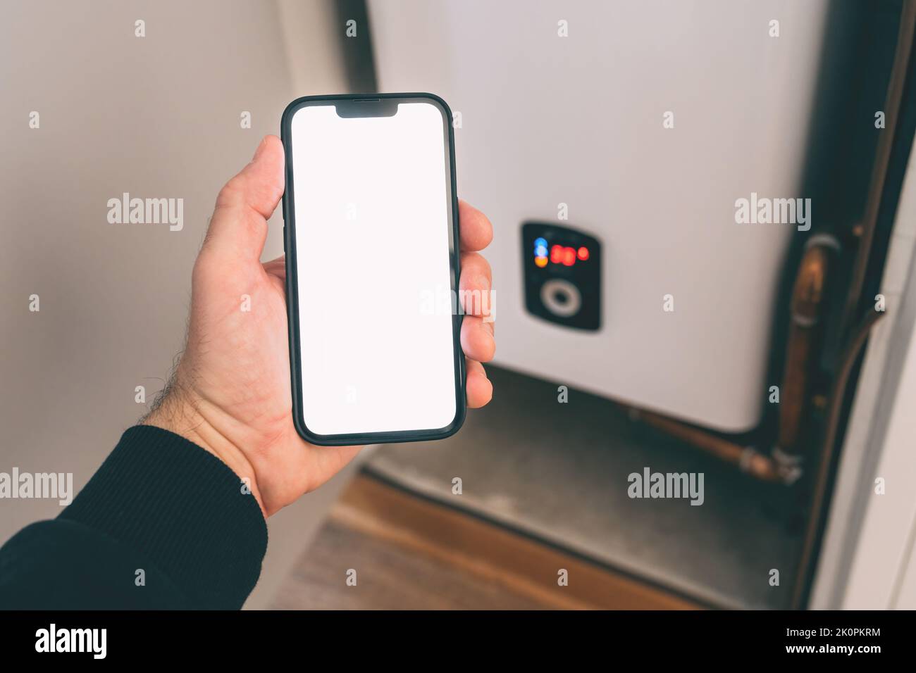 Smart home heating system, man holding smartphone with blank screen for Wi-Fi control app mockup, selective focus Stock Photo