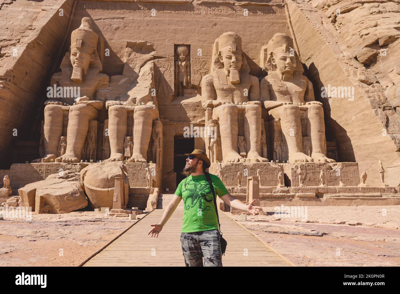 White Tourist in front of the Colossal Statues of Ramesses II seated on a throne near the entrance to the Great Temple at Abu Simbel, Egypt Stock Photo