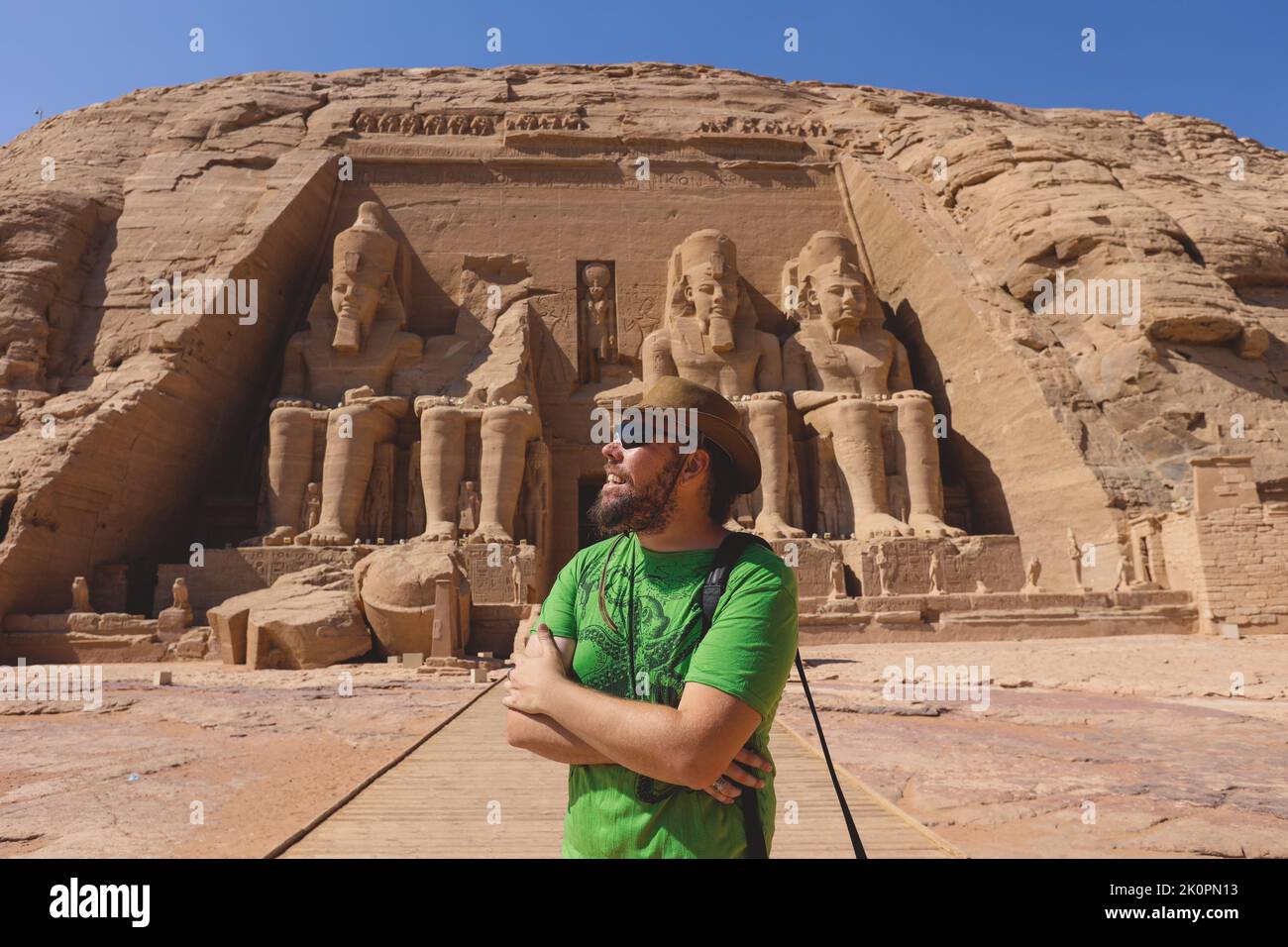 White Tourist in front of the Colossal Statues of Ramesses II seated on a throne near the entrance to the Great Temple at Abu Simbel, Egypt Stock Photo