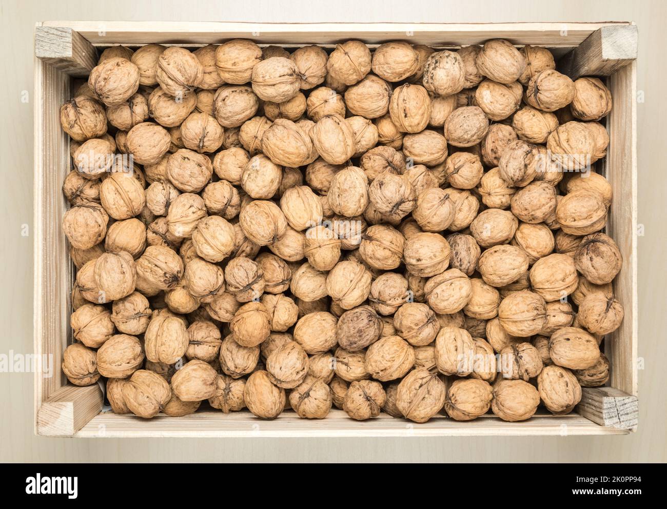 Wooden box filled with whole walnuts, view from above Stock Photo