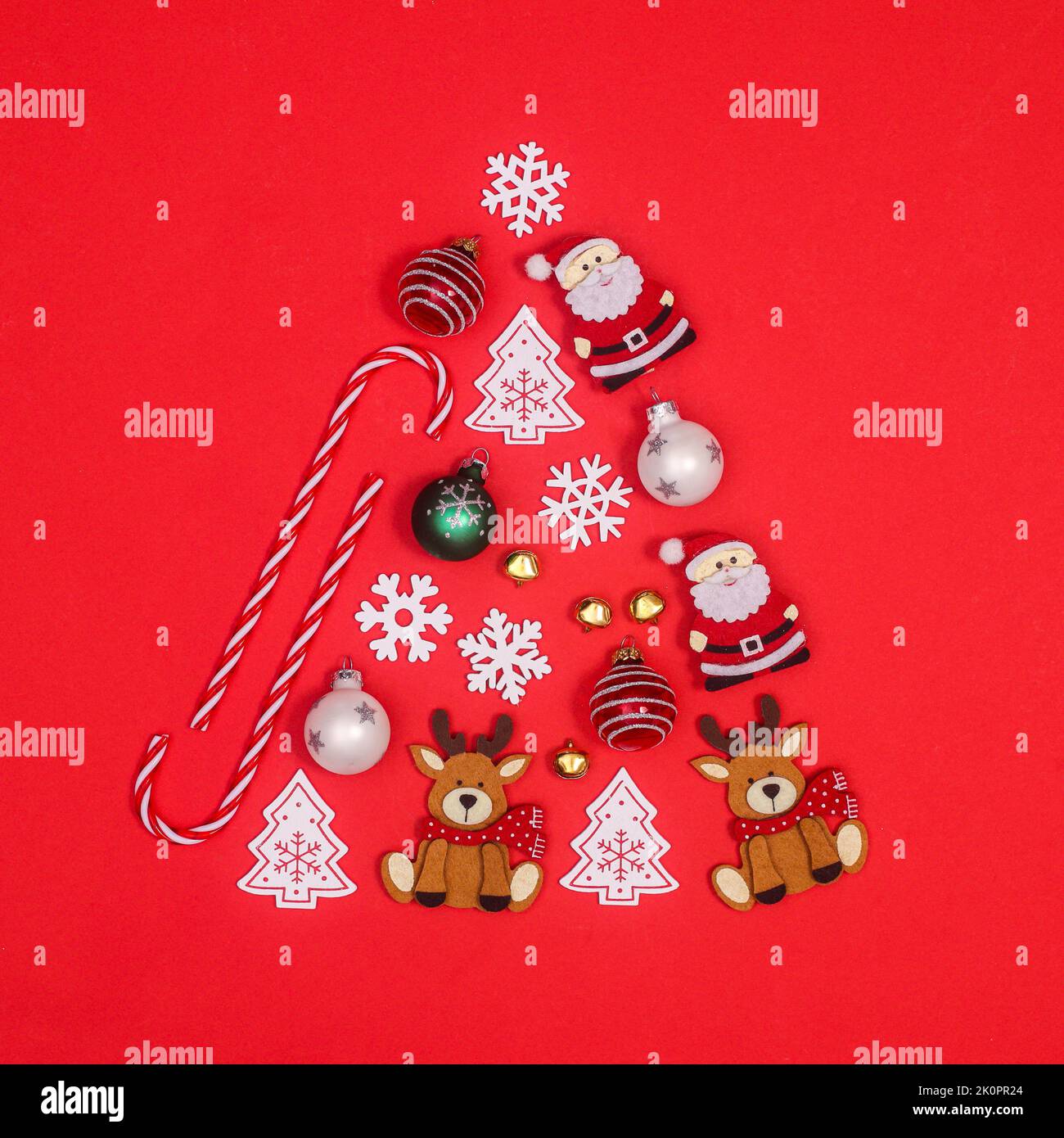 Creative Christmas tree shape made with various ornaments on red background. Flat lay Stock Photo