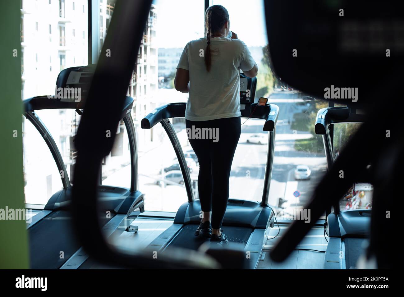 Plus size woman run on modern treadmill at fitness gym and look out