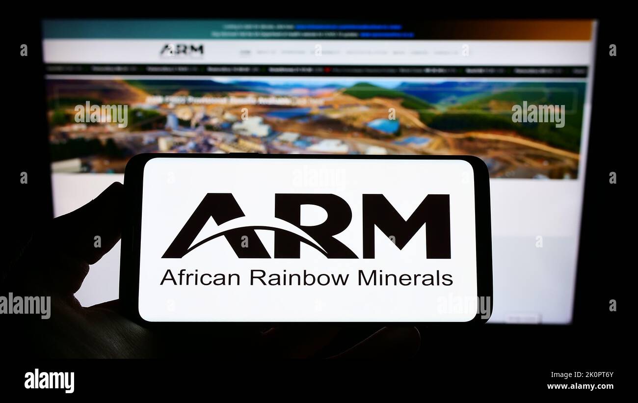 Person holding smartphone with logo of company African Rainbow Minerals