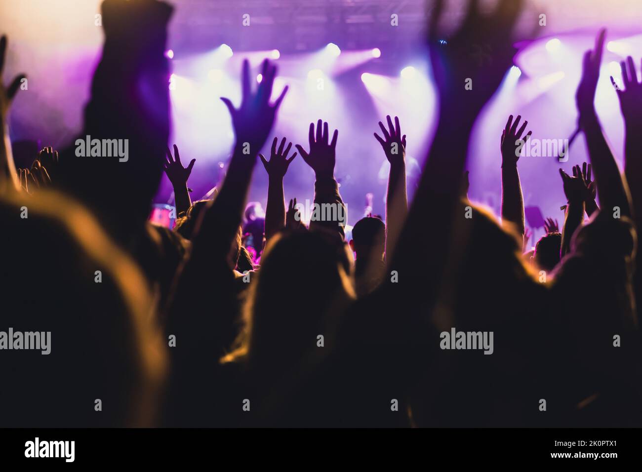 Crowd at concert - Cheering crowd in front of bright colorful stage lights Stock Photo
