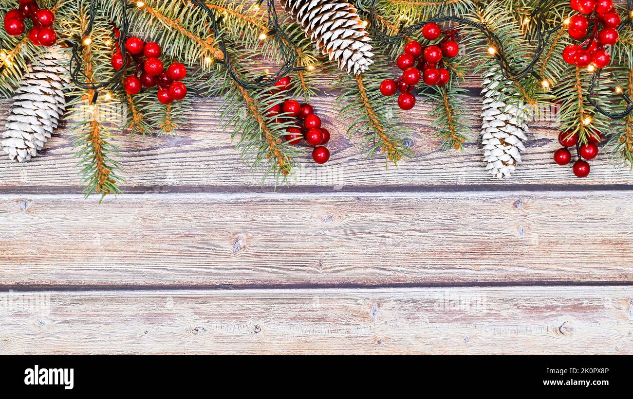 Wooden background with fir garland and red berries and pine cones. Copy ...