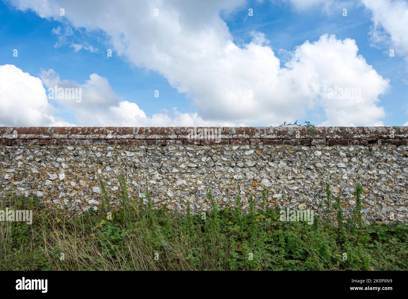 old flint and stone wall with sky background. Stock Photo